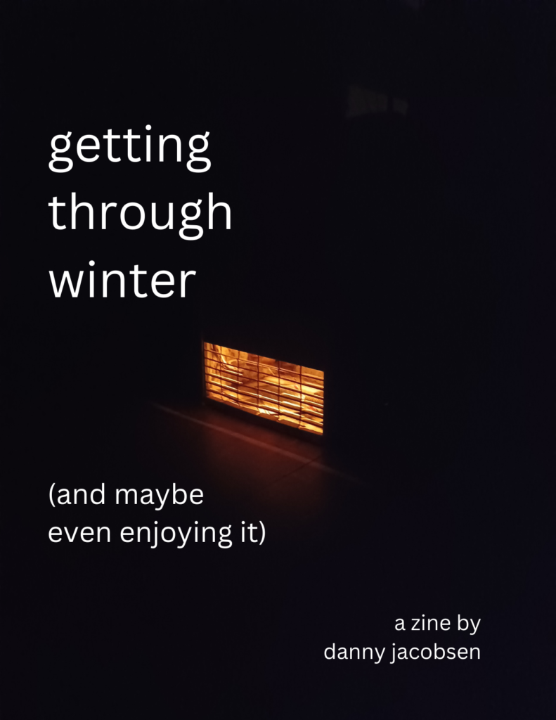 title text: getting through winter (and maybe even enjoying it) a zine by danny jacobsen. text is overlaid on an image of a pilot light of a house heater at night.
