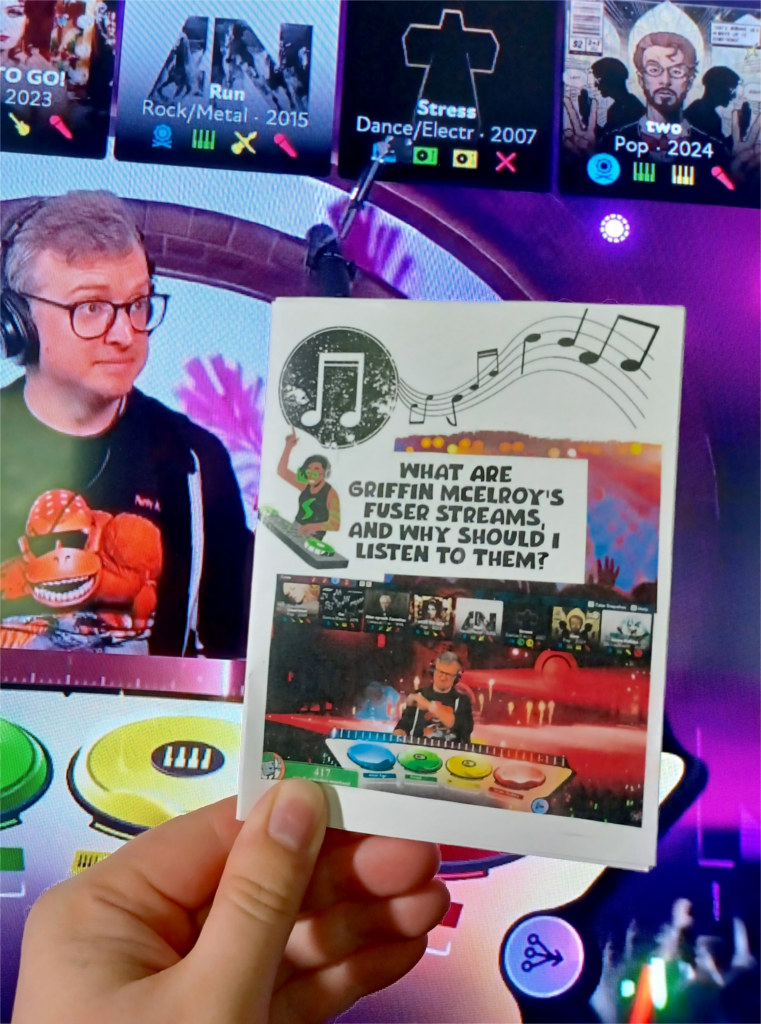 My hand holding an oversize minizine with the title "What are Griffin McElroy's Fuser streams, and why should I listen to them?" in front of one of Griffin McElroy's Fuser streams on a TV.